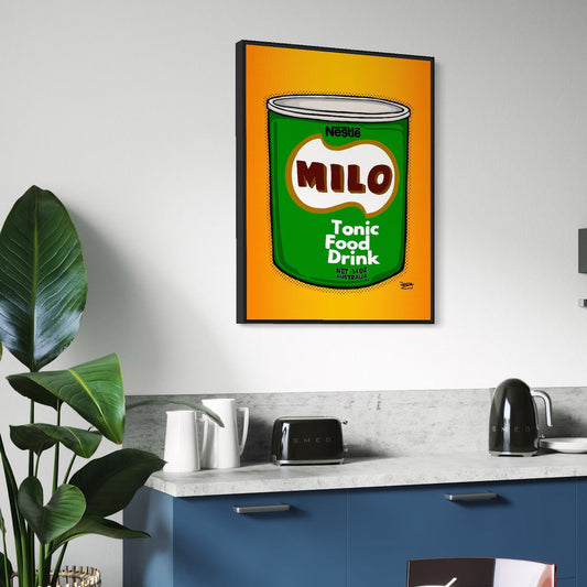 Framed artwork of a vintage Milo can on a kitchen wall with blue cabinets and a plant.