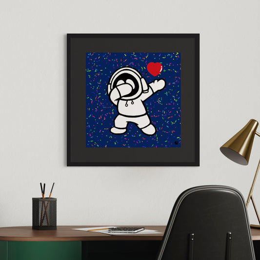 Framed artwork of Hoodie Boy dabbing with a red heart on a blue background with colorful sprinkles, displayed on a wall above a desk.