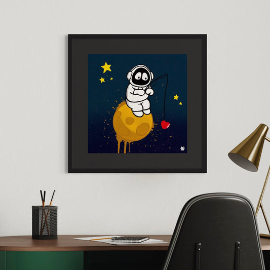 Framed colorful artwork of Hoodie Boy sitting on the moon fishing pole in hand with a heart at the end of the line, above a desk.