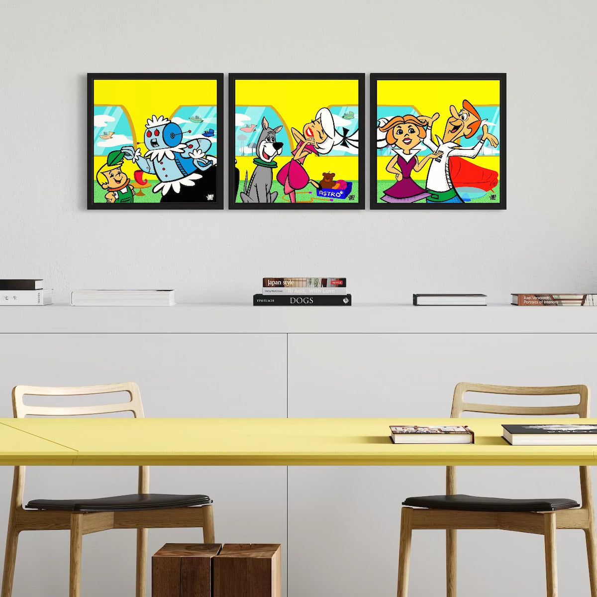 Three colorful framed artworks on a wall above a table with chairs.
