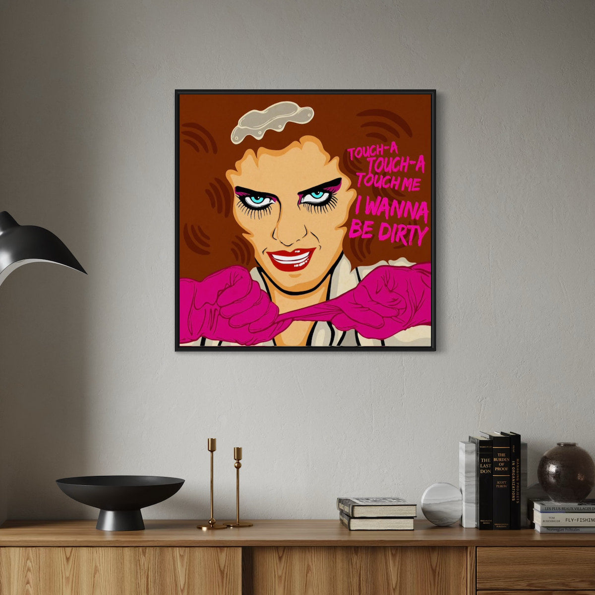 Framed artwork of Magenta from Rocky Horror with text on a wall above a wooden cabinet.