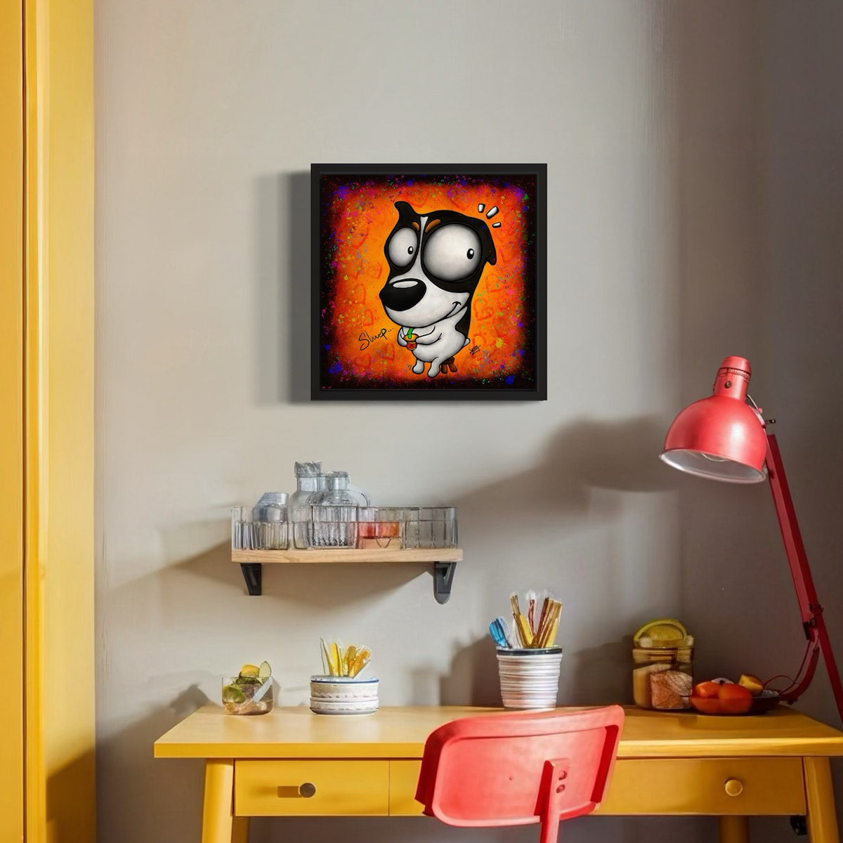 Framed artwork of a cartoon dog slurping on a drink with colorful orange background, above a desk with a red chair and lamp.