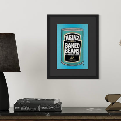 Framed Heinz baked beans artwork on a shelf with books and a lamp.