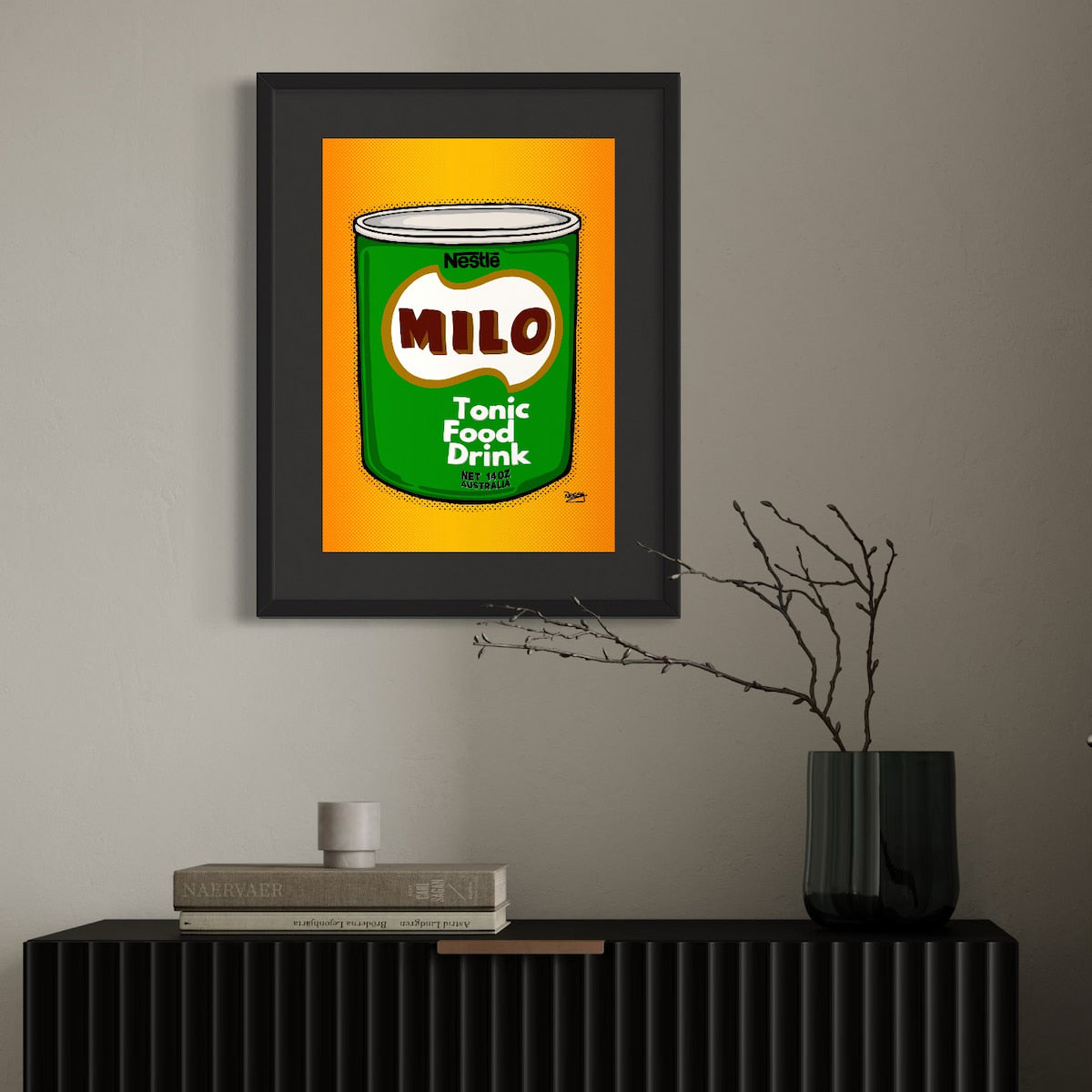 Framed artwork of a Milo can on a wall above a black cabinet.