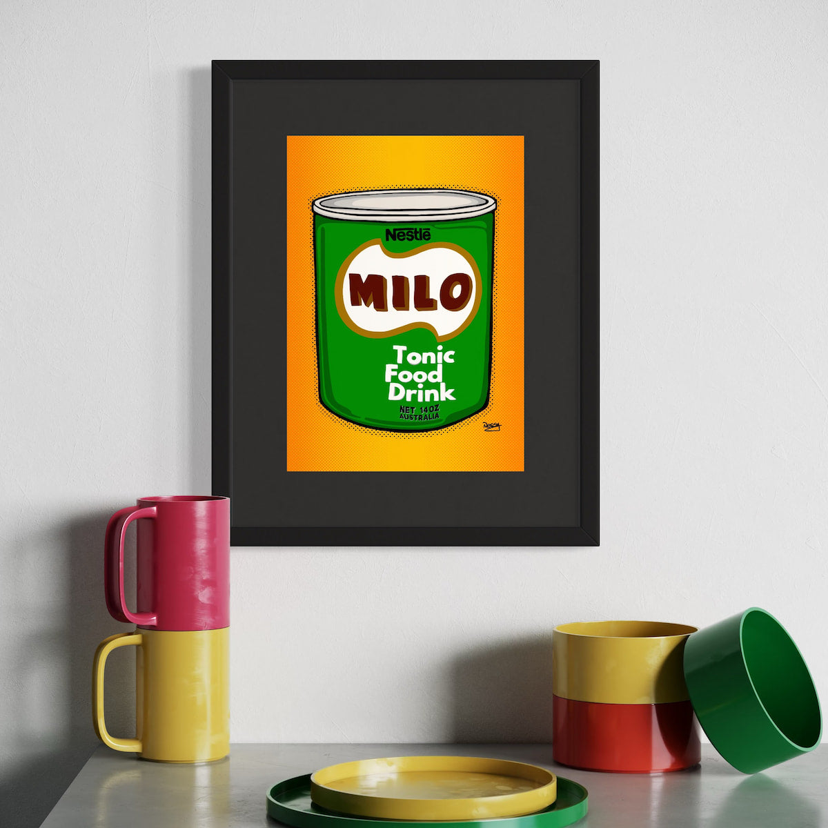 Framed artwork of a Milo can with colorful mugs and containers on a white surface.