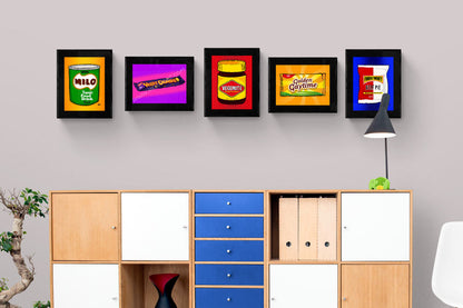 Framed vintage food packaging art on a wall above a wooden cabinet.