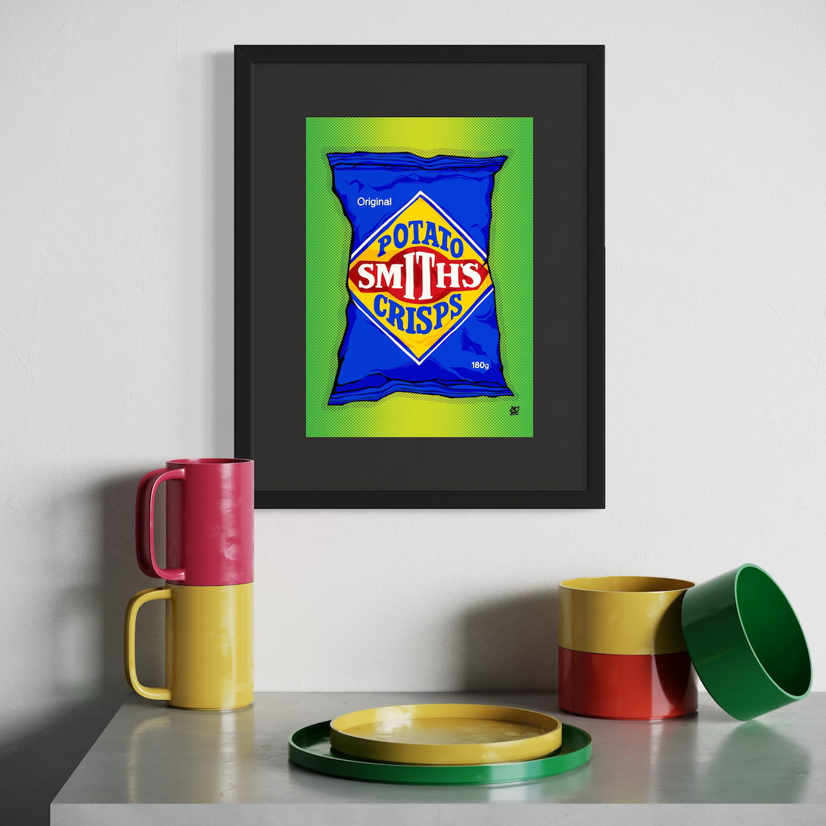 Framed artwork of a blue packet with 'Smith's Crisps' text on a white wall, with colorful mugs and plates below.