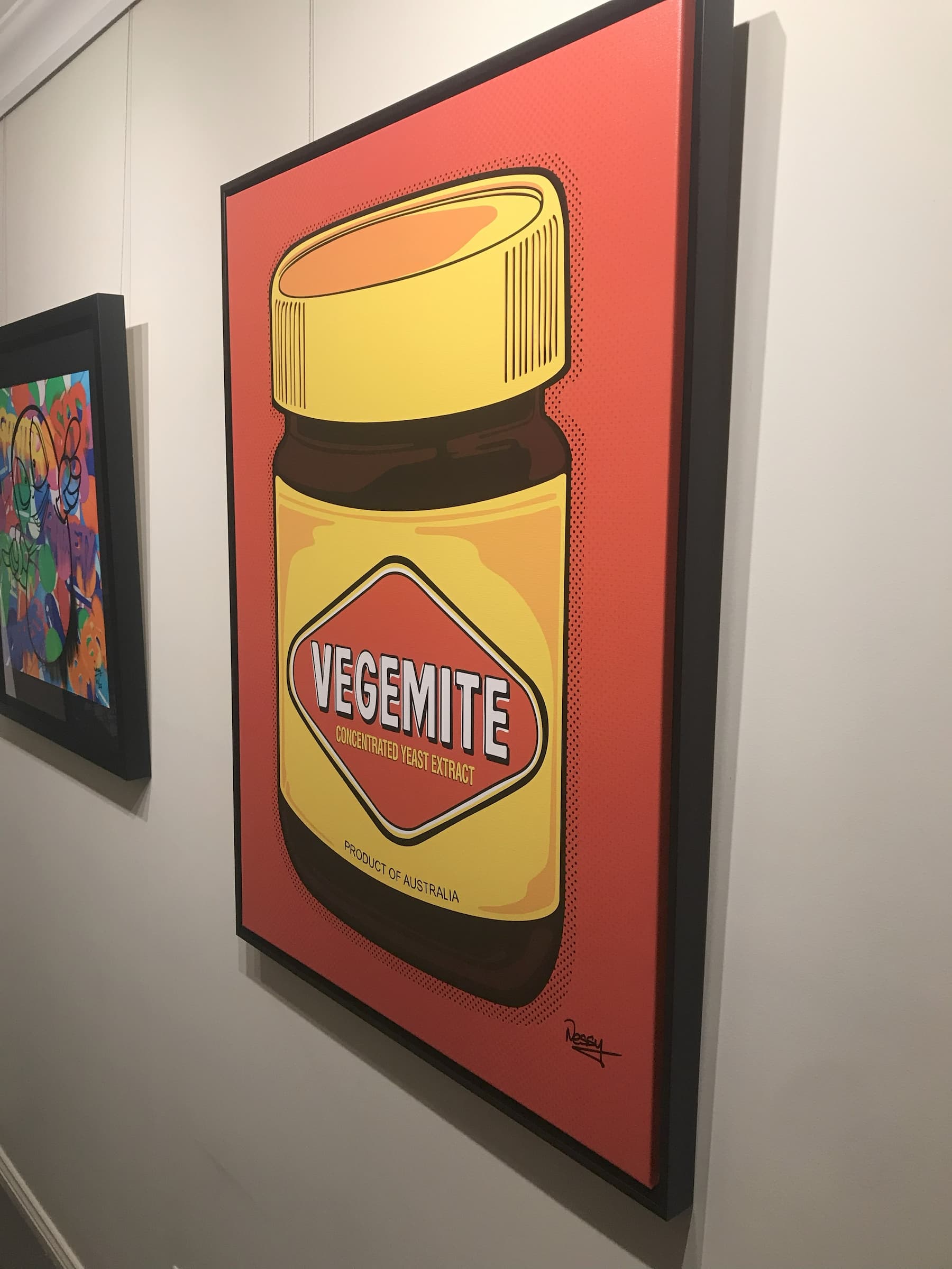Vegemite in full pop—yellow lid, red diamond, and Aussie pride dialed to eleven. Framed canvas, 100×75cm from Nessy Pop Art, signed and mounted beside a splash of abstract colour. A national icon with gallery-grade swagger.