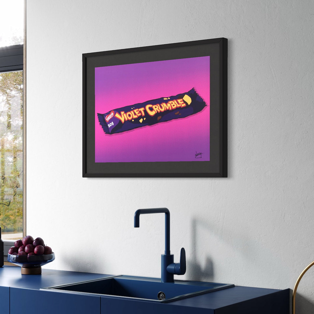 Framed artwork of a Violet Crumbles candy bar on a kitchen wall above a sink.