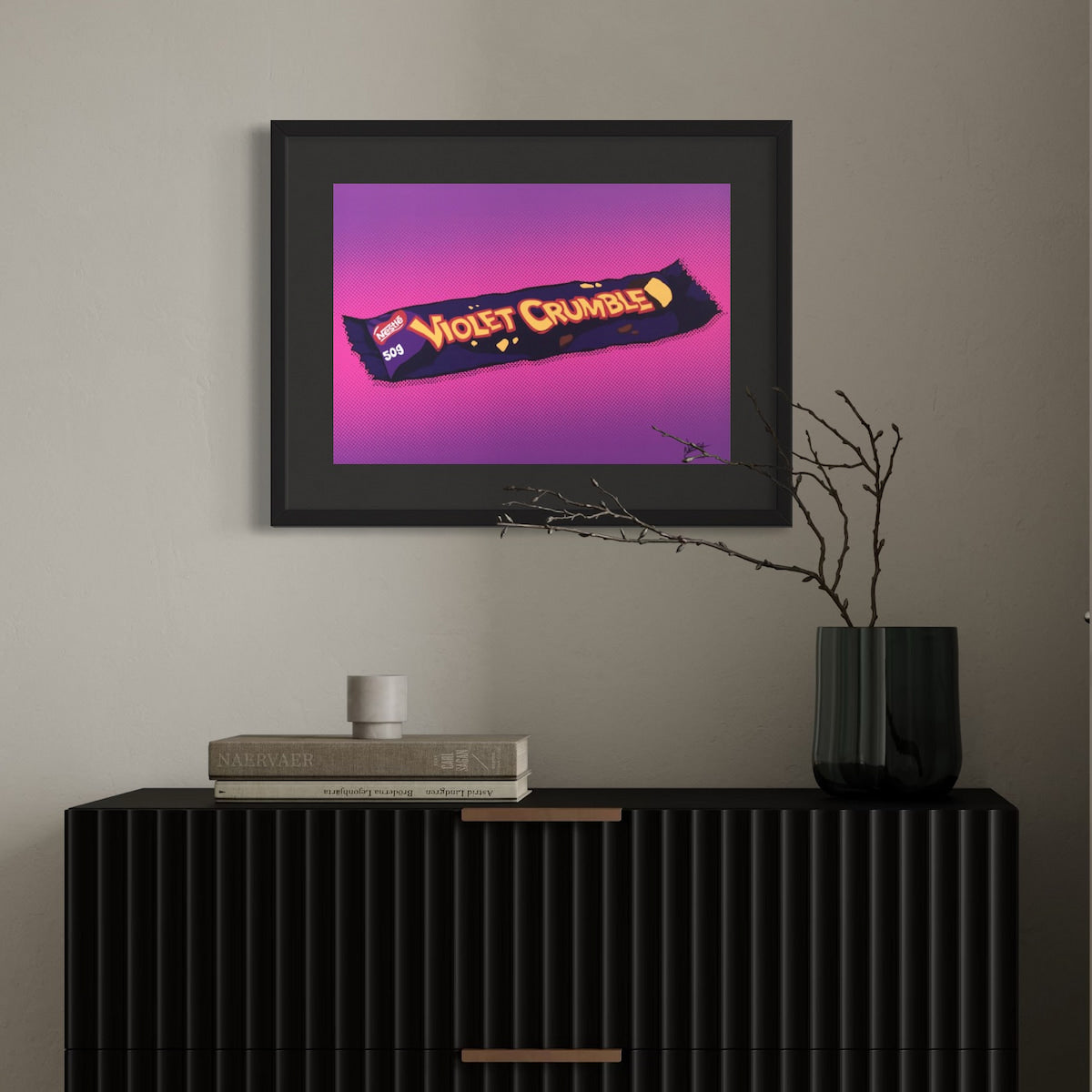 Framed artwork of a Violet Crumble candy bar on a wall above a black cabinet.