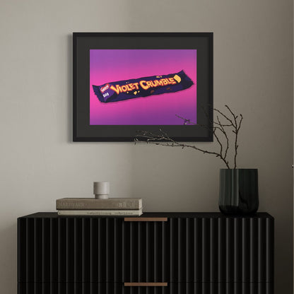 Framed artwork of a Violet Crumble candy bar on a wall above a black cabinet.