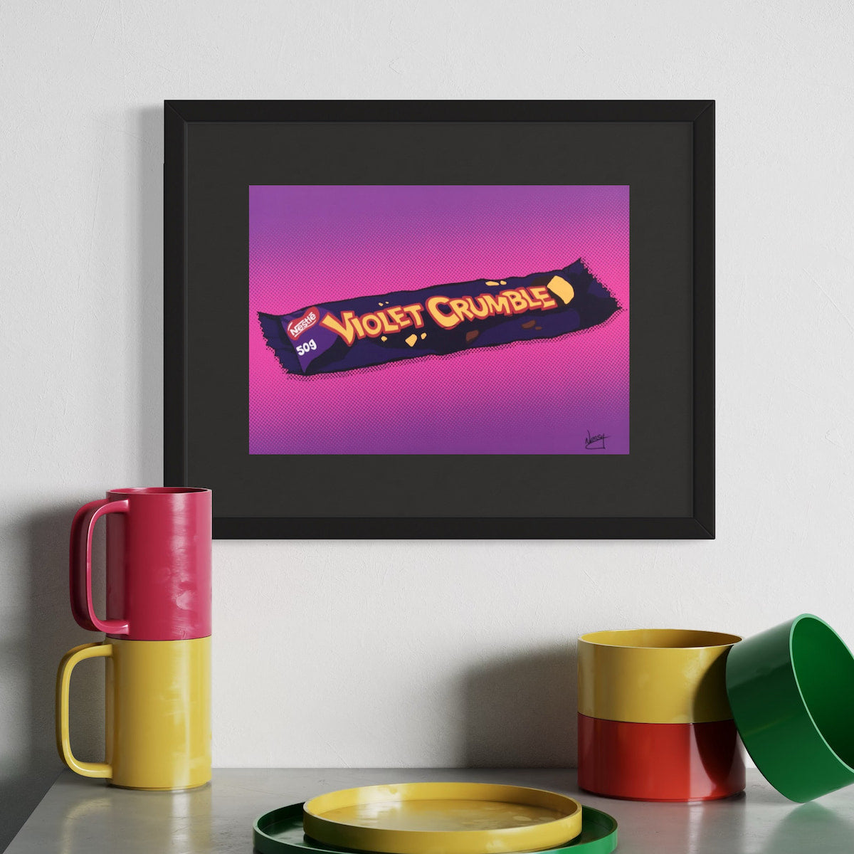 Framed artwork of a Violet Crumble candy bar with colorful mugs and bowls on a table.