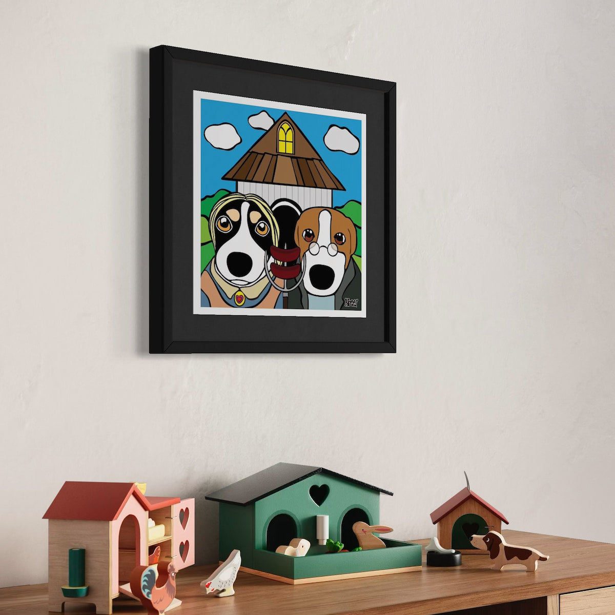 Two dogs in front of triangular-roofed house—playful cartoon homage to American Gothic with expressive faces, blue sky, and yellow window. Staged above shelf of colorful house-shaped decor and animal figurines. Giclée print, 30x30cm from Nessy Pop Art