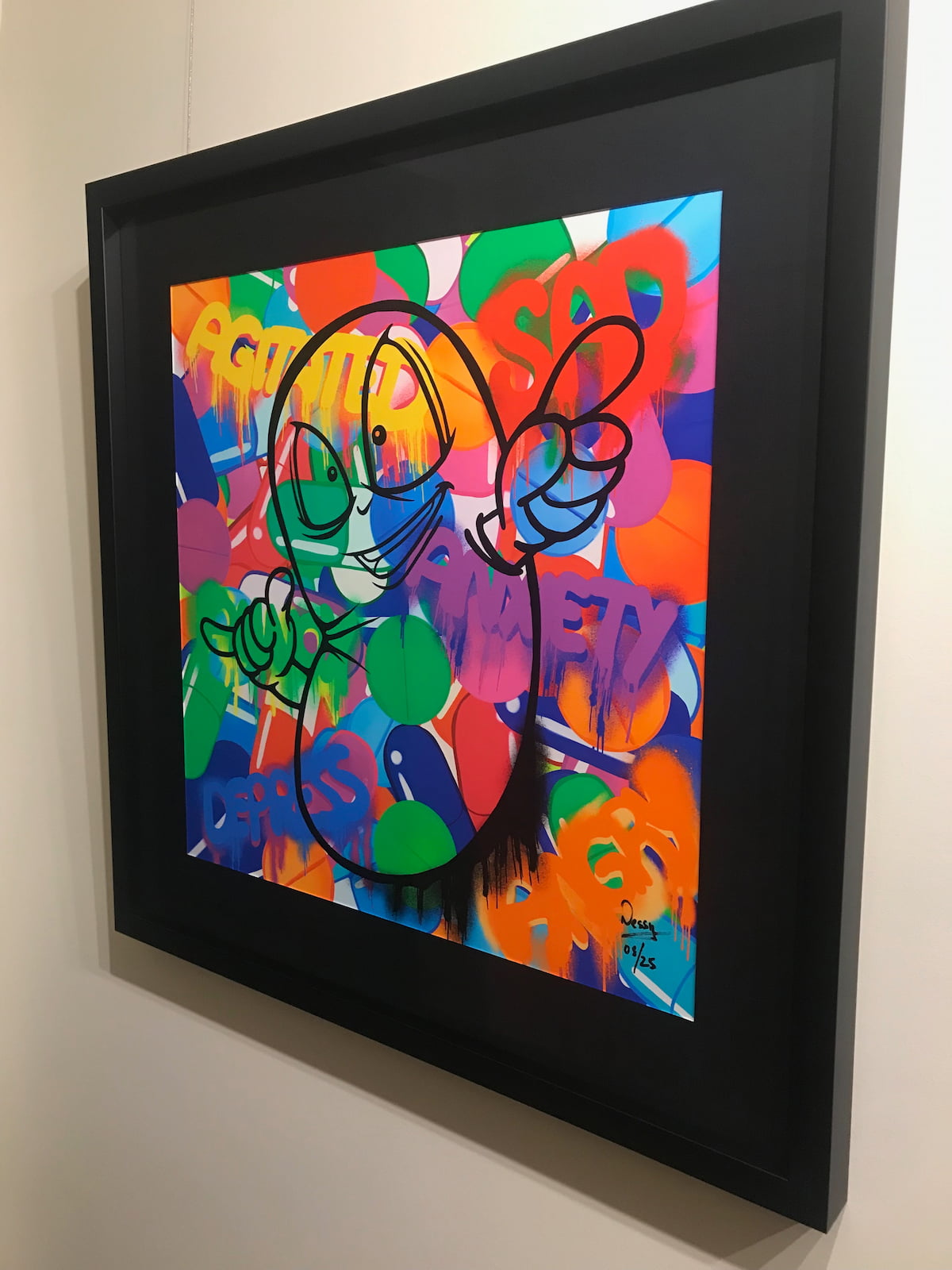 Framed colorful artwork of a pill character overcoming depression and anxiety, on a white wall