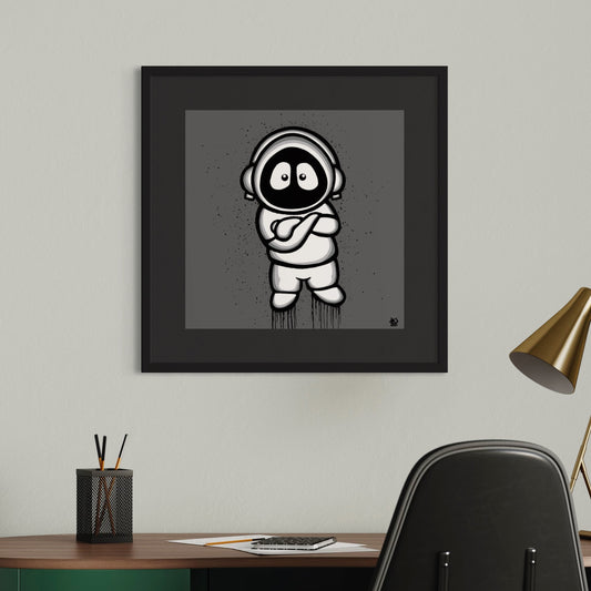 Framed black and white illustration of Hoodie Boy, arms folded, with a gray background, on a white wall above a desk.