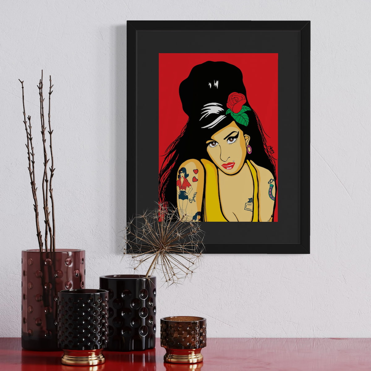 Framed artwork of Amy Winehouse on a wall with decorative vases below.