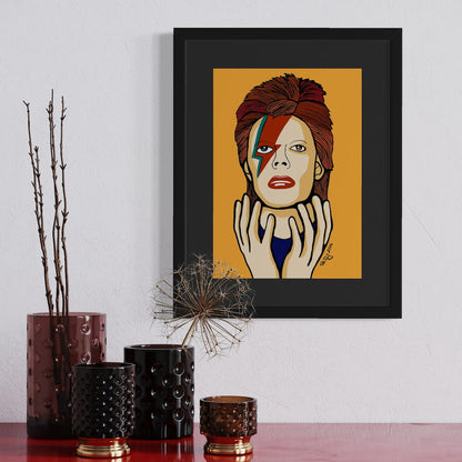 Framed artwork of David Bowie with a colorful face on an orange background, displayed on a wall above decorative vases.