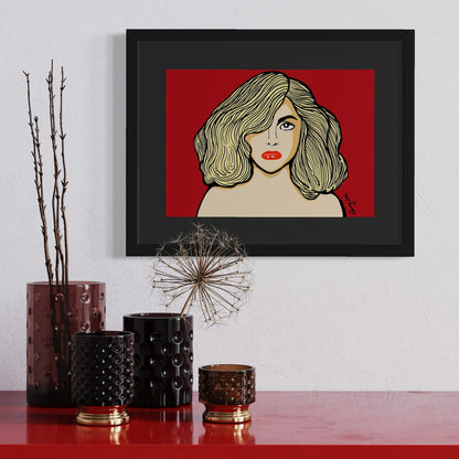 Gaga in red—blonde waves, bold lashes, and lips that dare. A4 giclée from Nessy Pop Art, framed above a red shelf with sculptural vases and dried botanicals. A pop icon rendered in pure attitude