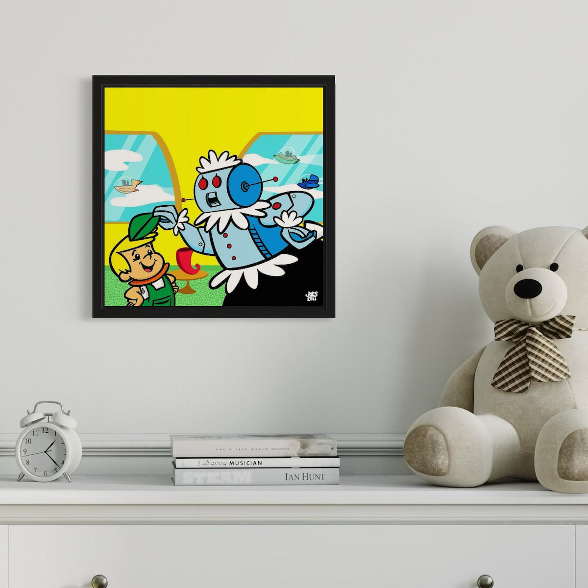 Framed cartoon print on a wall above a shelf with a teddy bear and books.