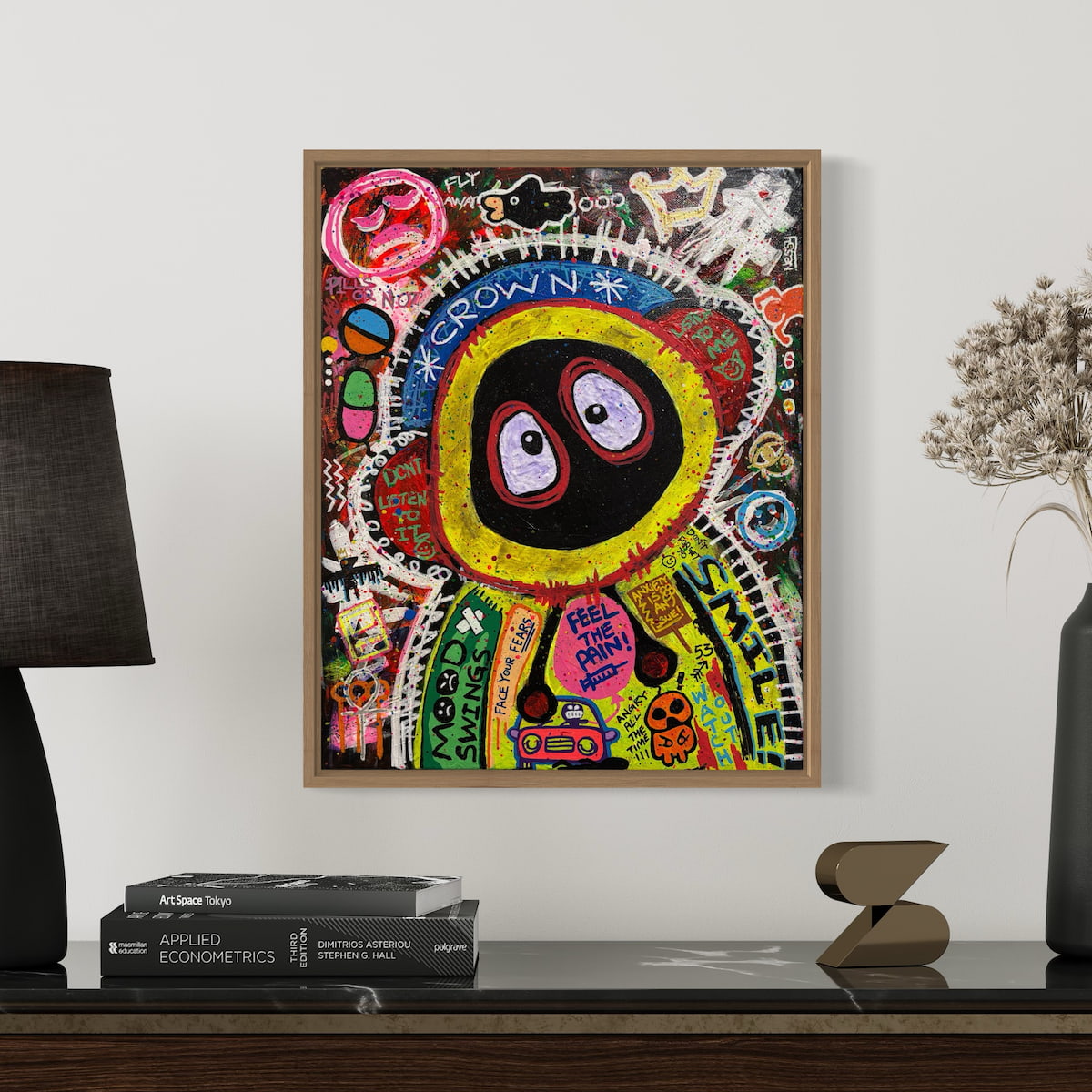 Colorful painting of Hoodie Boy in a Basquait style on a wall above a shelf with books and decor items.