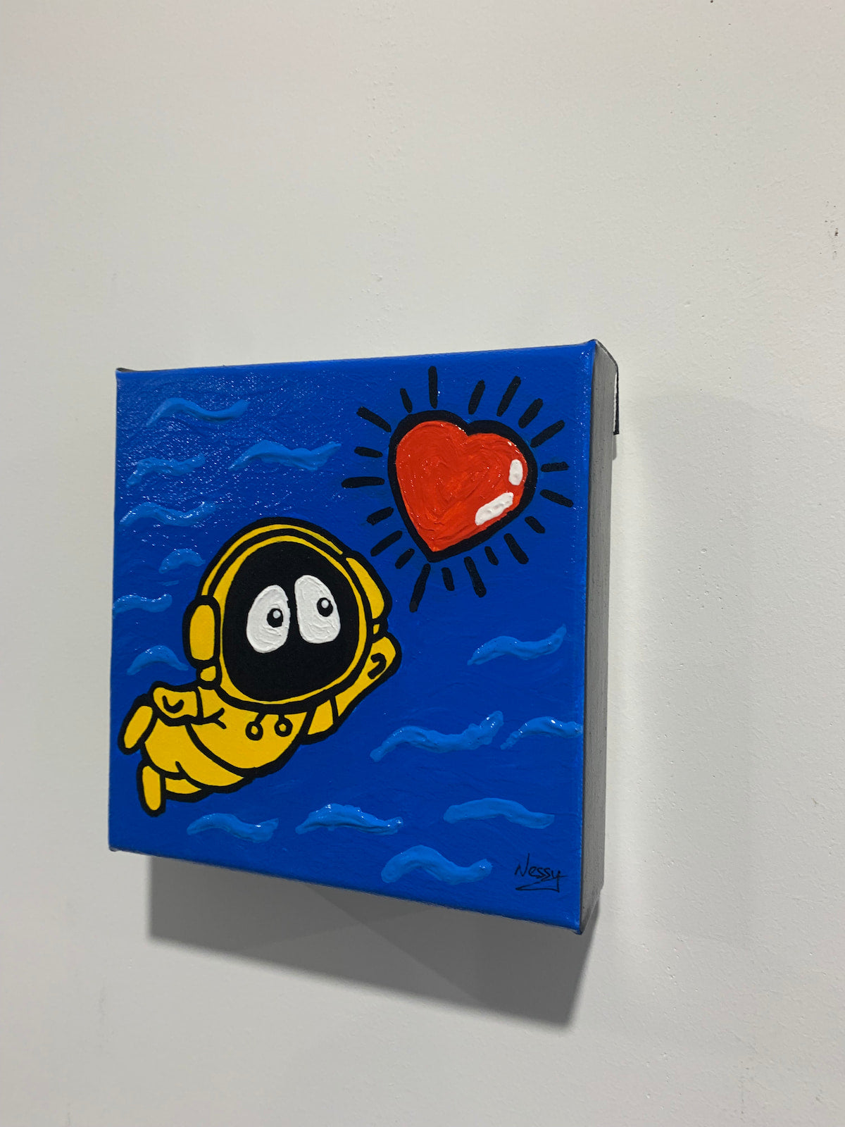 A colorful painting of Hoodie Boy swimming towards a shinning heart, from the side on a white wall.