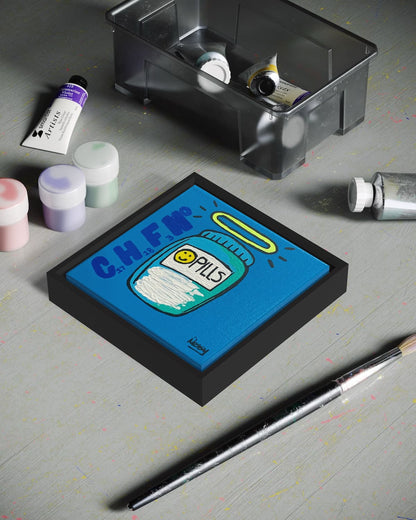 Artistic depiction of a pill container with colorful design on a gray surface with art supplies.
