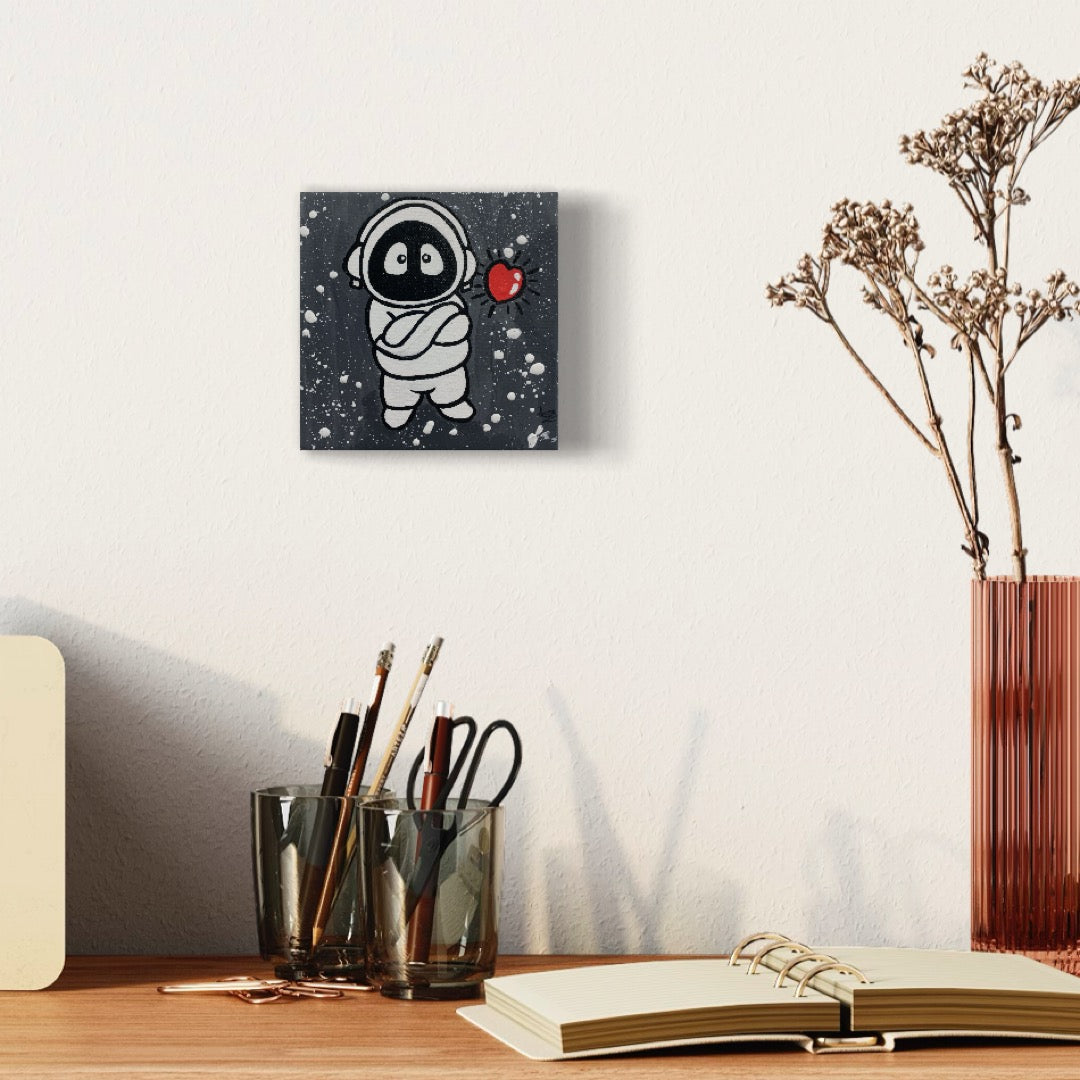 Painting of Hoodie Boy, arms folded, with a floating heart, on a wall above a desk.