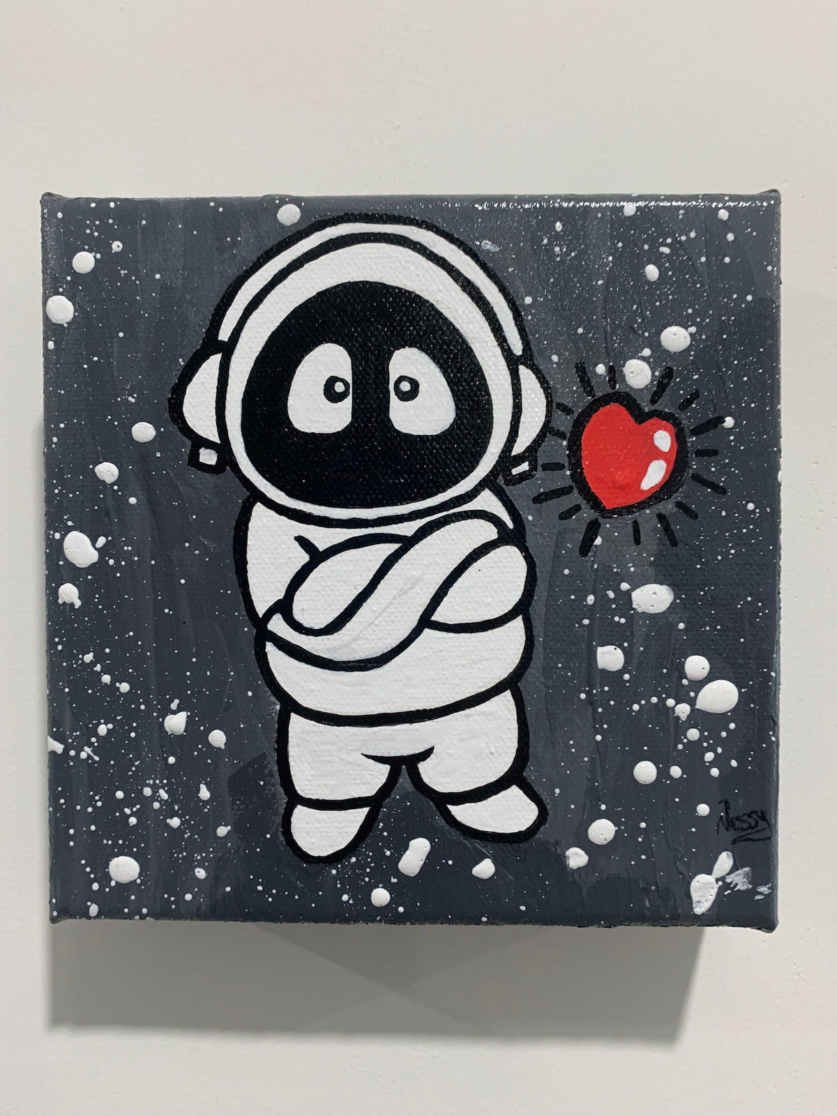 Painting of Hoodie Boy, arms folded, with a floating heart, on a white wall.