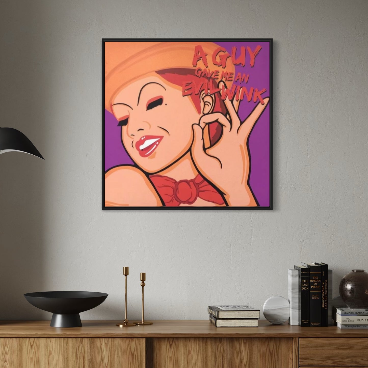 Framed artwork of Columbia from Rocky Horror with text on a wall above a wooden shelf.