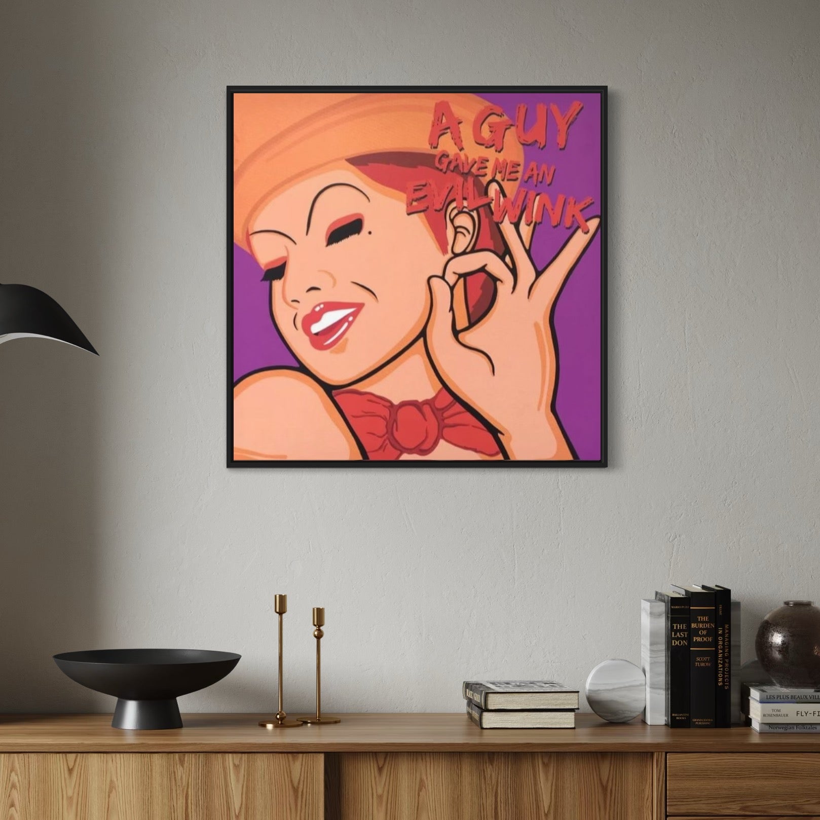Framed artwork of Columbia from Rocky Horror with text on a wall above a wooden shelf.