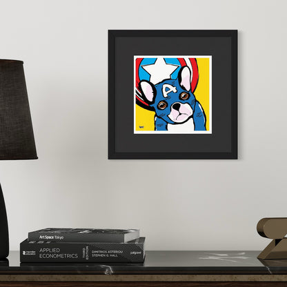 Framed artwork of a dog dressed as Captain America with a colorful design on a wall above books.